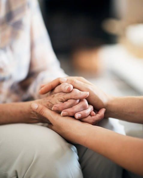 Cropped shot of an unidentifiable nurse consoling her elderly patient by holding her hands at home